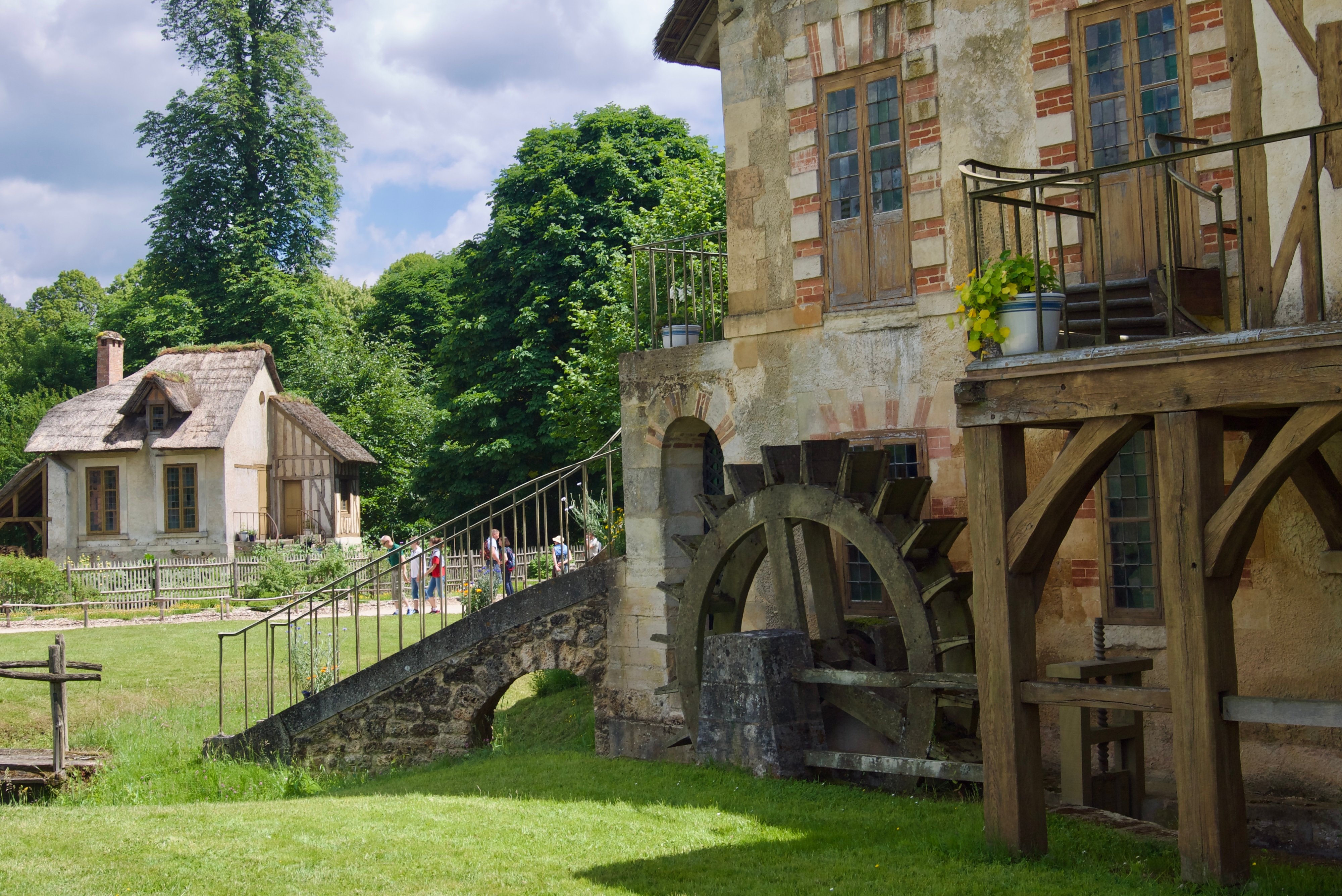 A ristic house with a water wheel on the side in the Domain of Marie Antoinette at Versailles.